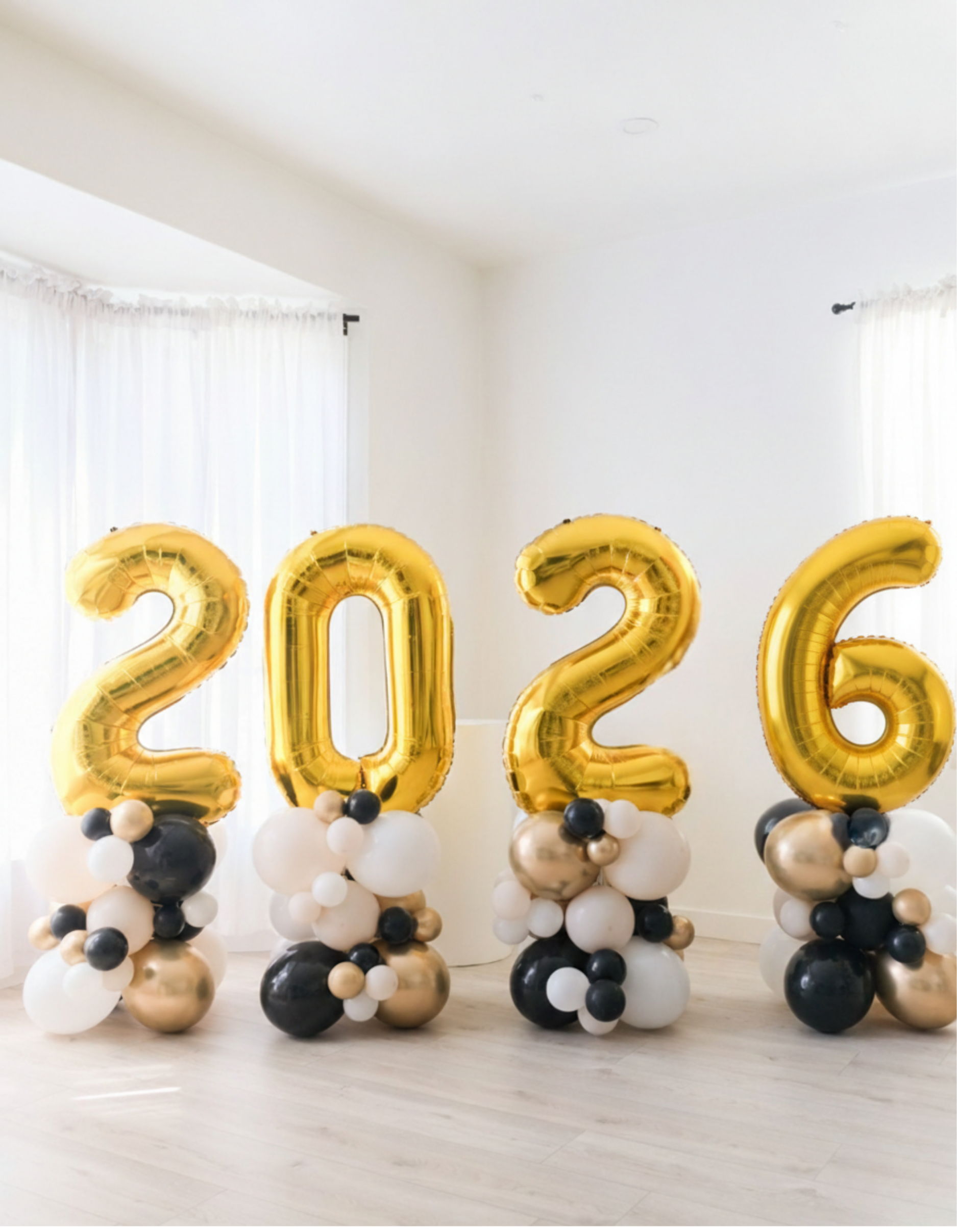 Gold '2026' balloons with black and white balloons on a light background