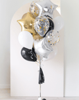 assorted graduation balloons in black, white, gold in front of an arch backdrop