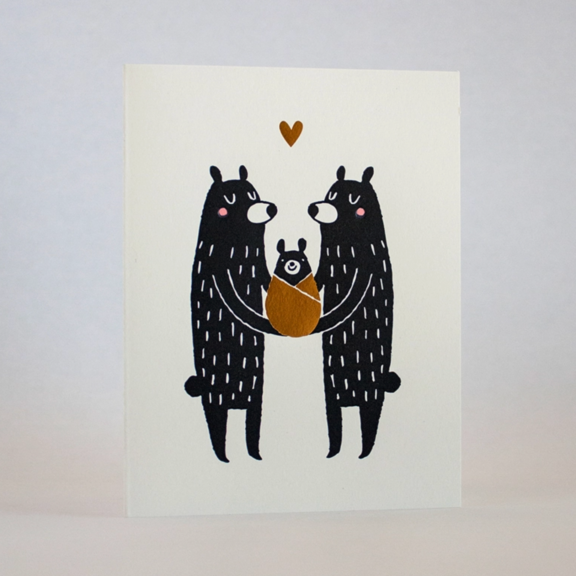 A greeting card with two big bears holding a baby bear and a gold heart above them