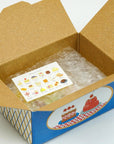 Open cardboard box with a blue base and clear plastic cover containing a card with illustrations.