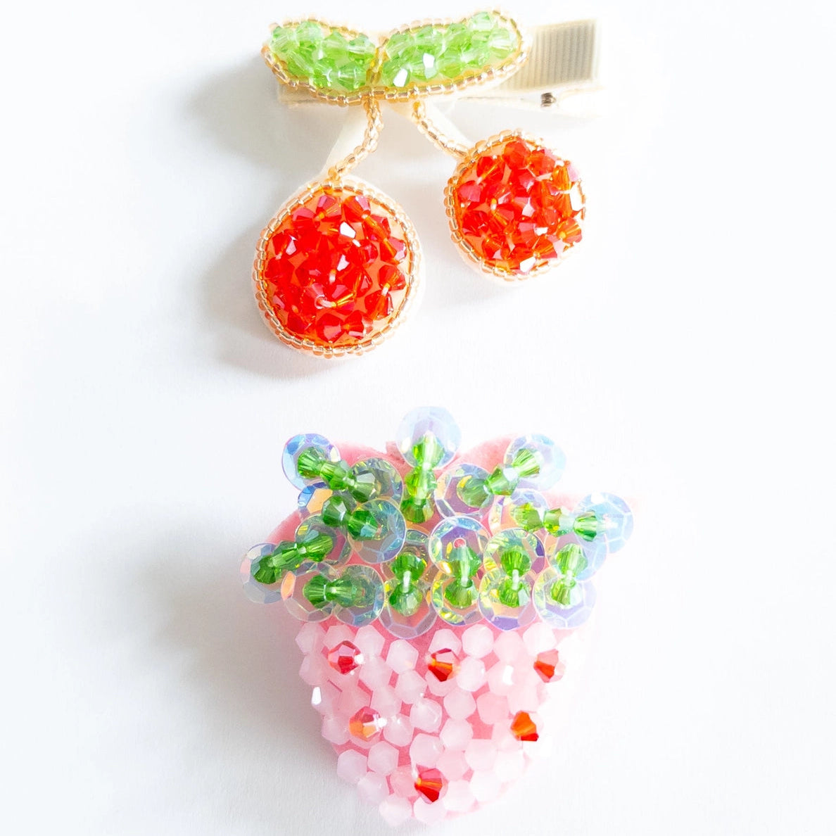 Beaded hairclips of strawberry and cherry on a white background.