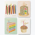 A set of four birthday cards with colorful candle designs, placed outside a paper-wrapped box with gold foil accents.
