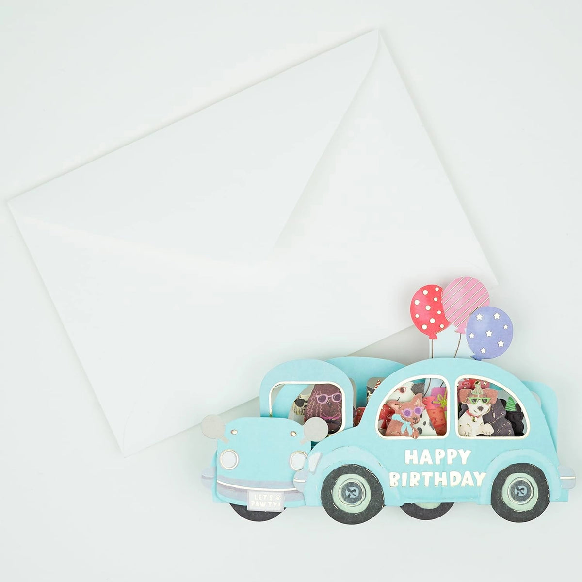 pop up 3d card featuring blue car with dogs inside, "happy birthday" text on the side, with white envelope