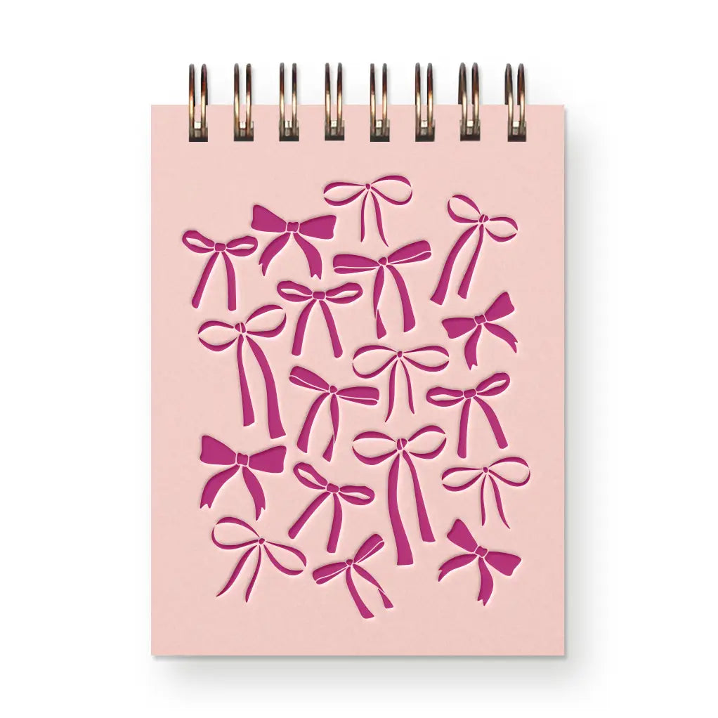 Pink notebook with bow pattern on a white background