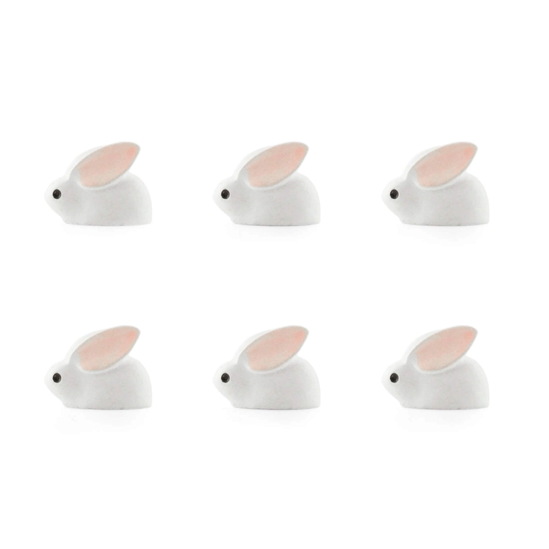 Six small white bunny-shaped items arranged in two rows on a plain white background. Each bunny has a pale pink inner ear, a small black eye, and a subtle shadow underneath.
