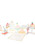 A greeting card designed to look like a variety of cakes with decorations and a text that reads 'HAVE YOUR CAKE AND EAT IT TOO'. The card is folded and displayed with a mint envelope.