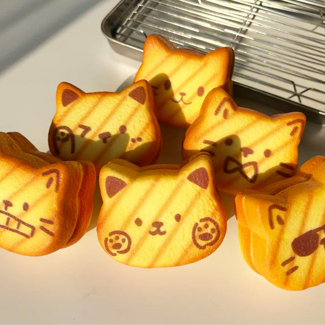 Cat-shaped baked goods squishy toy with facial expressions on table