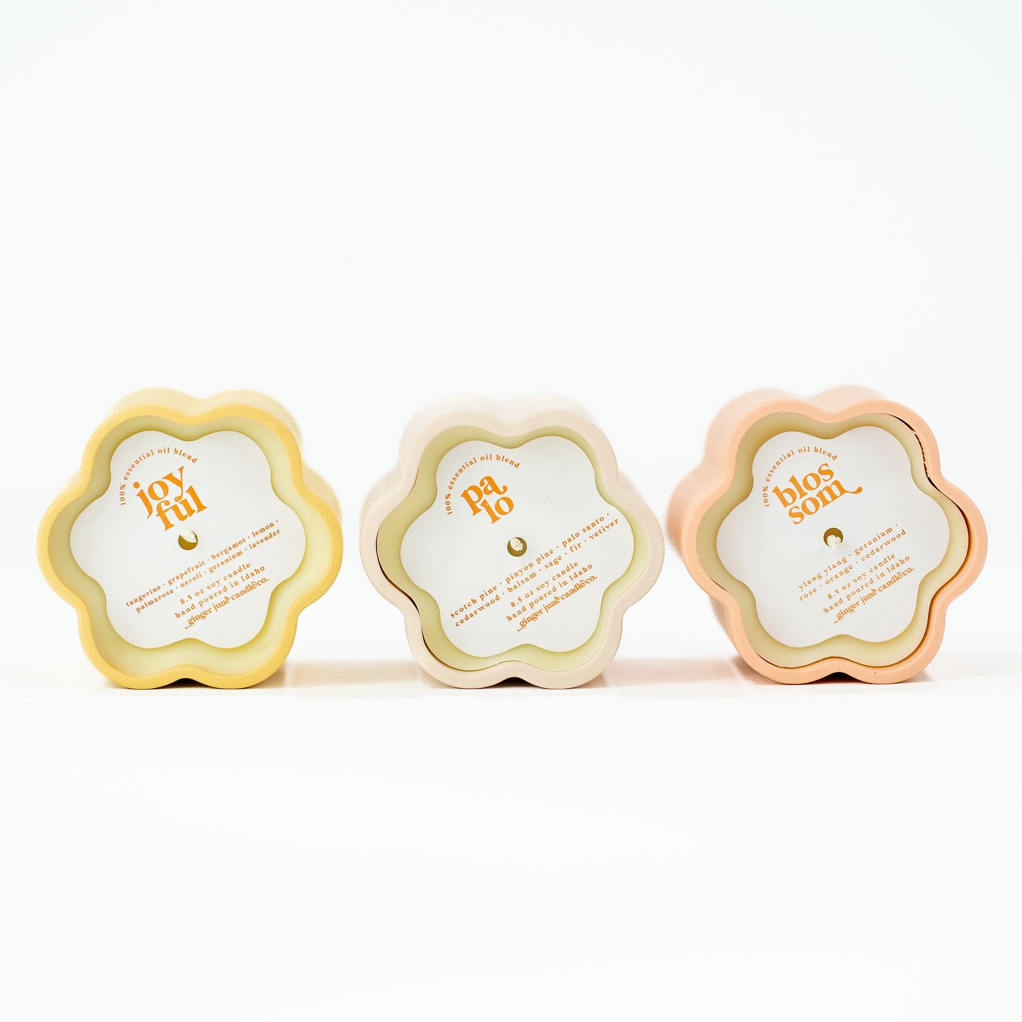 Three floral-shaped candles in pastel colors with labels on a white background