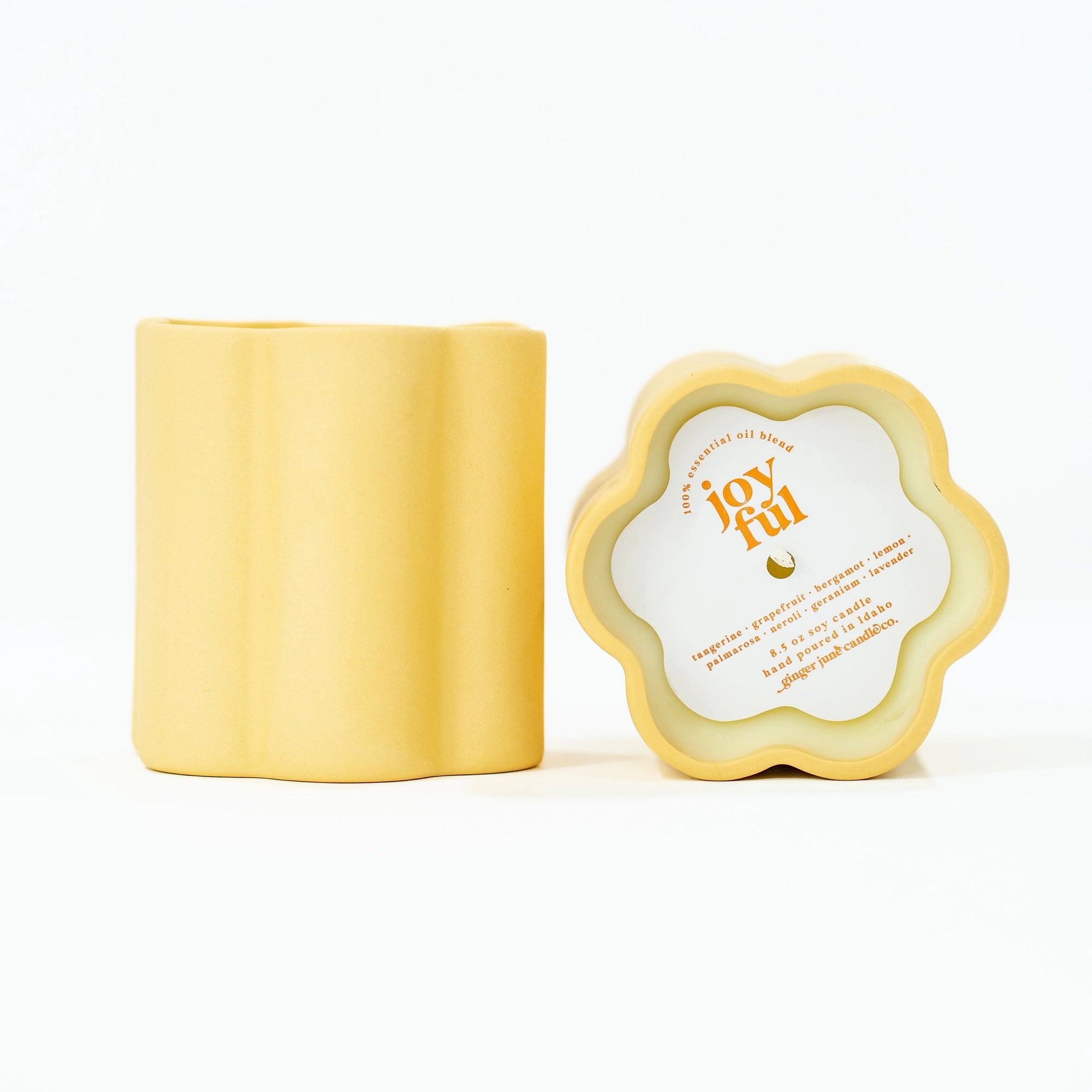 Yellow container of a candle's side view and top view. Top view has paper cover of scent and text