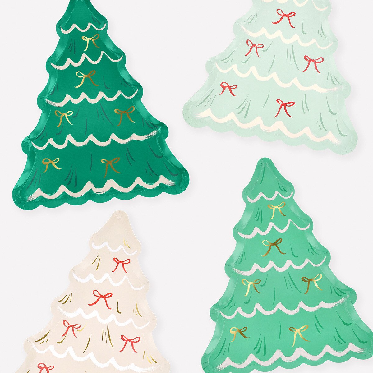 Four assorted color Christmas tree shaped plates with printed bows on a white background