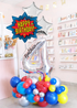 Birthday balloon arrangement with 'Happy Birthday' sign and number '4' balloon in a store setting.