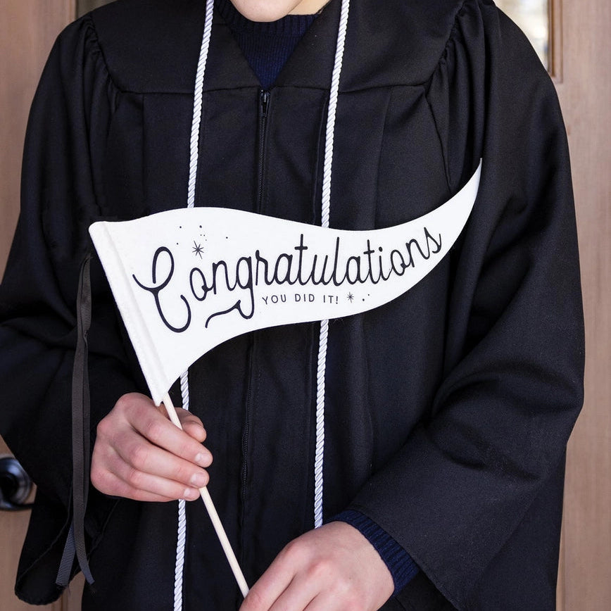 graduate holding "congratulations you did it!" pennant flag