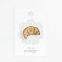 Croissant pin with a smiley face on a white background