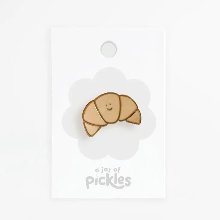 Croissant pin with a smiley face on a white background