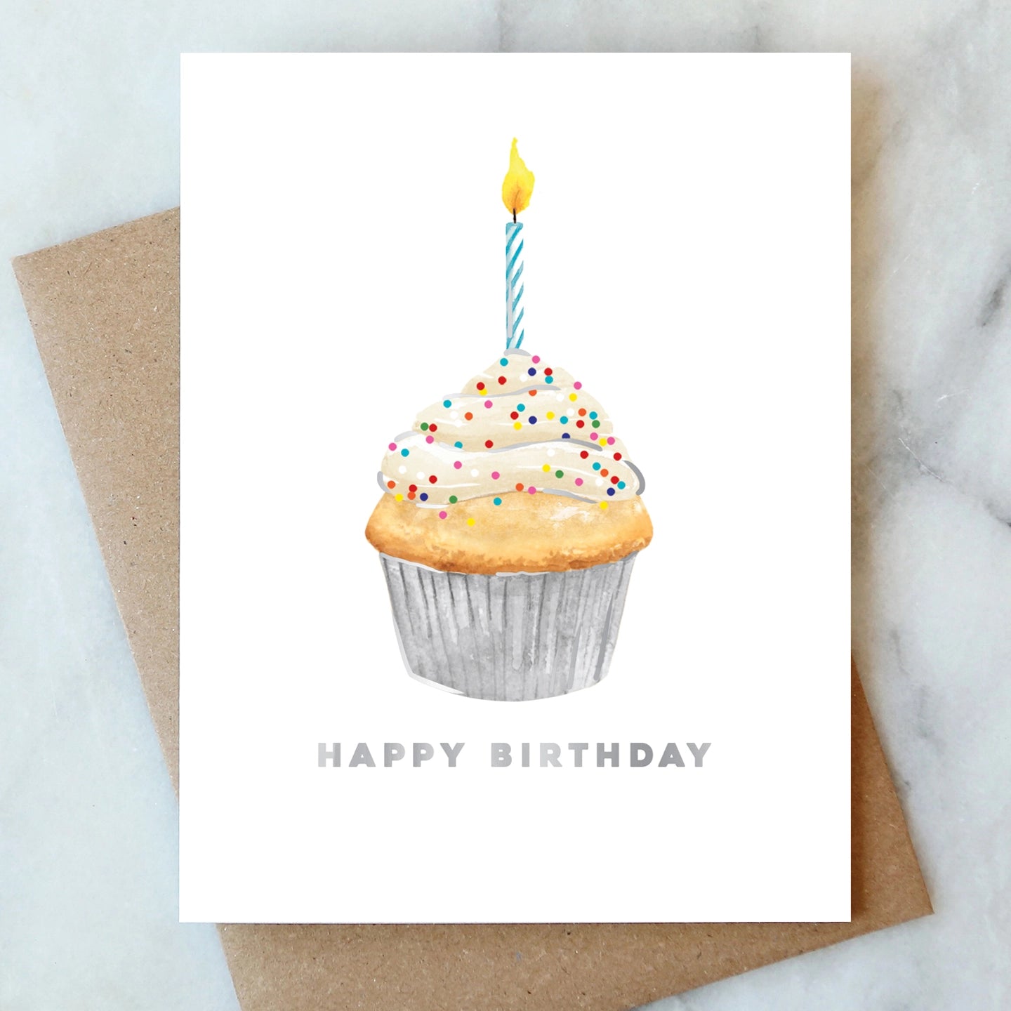 Birthday card with a cupcake illustration and 'Happy Birthday' text on a marble surface.