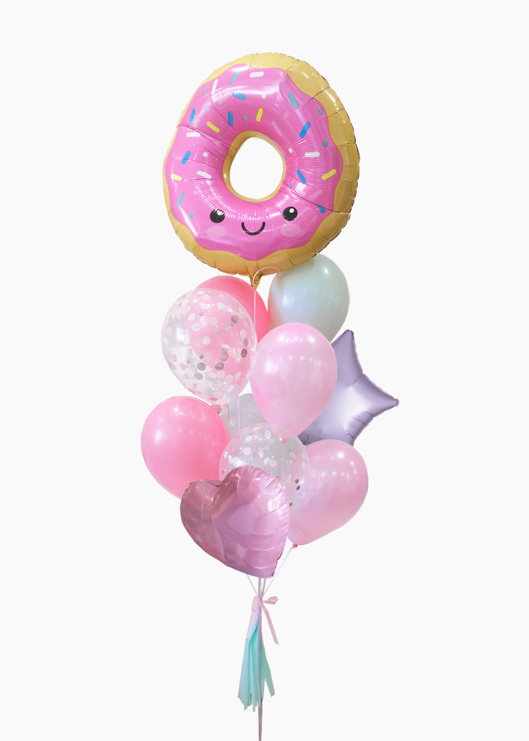 A  pink donut-shaped foil balloon with sprinkles and a smiling face, arranged together with latex balloons in pink and lavender, a translucent confetti balloon, a lavender star balloon, a pink heart balloon, and a tassel.