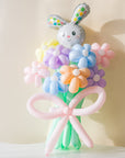 A balloon bouquet featuring a cute, cartoon-style bunny balloon with a bow, surrounded by various round balloons in pastel colors.
