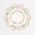 A white ceramic side plate with a floral pattern and gold foil details along the border.