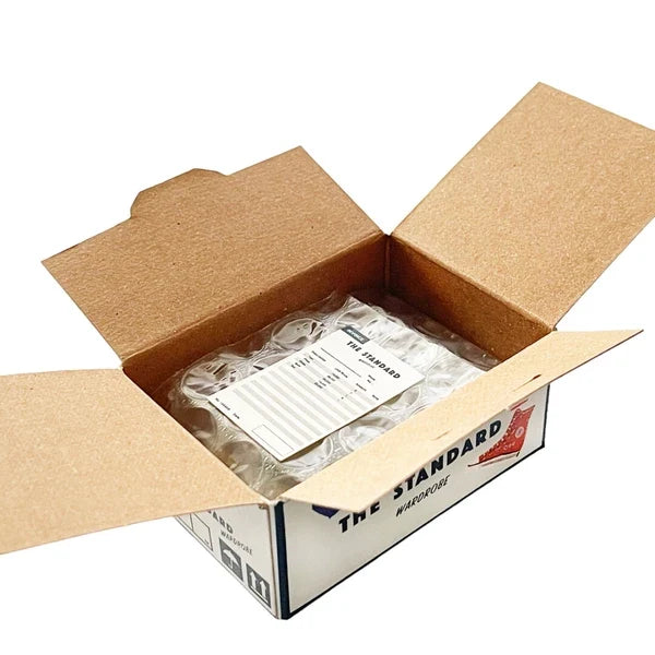 Open cardboard box with a clear plastic bag containing items, branded 'The Standard'.