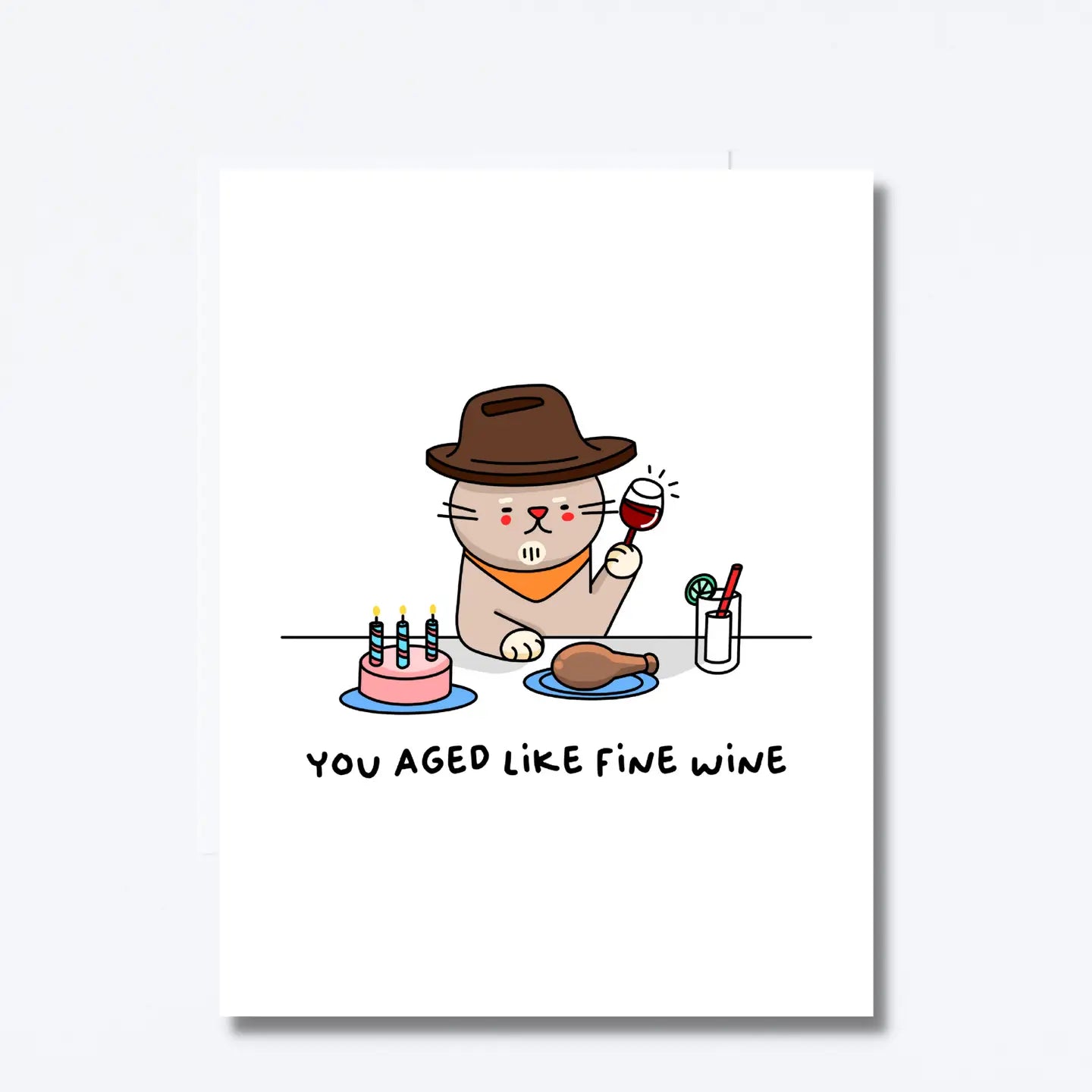 Cartoon cat in a hat with a glass of wine, cake, and chicken on a table with text 'You aged like fine wine' on a white background.