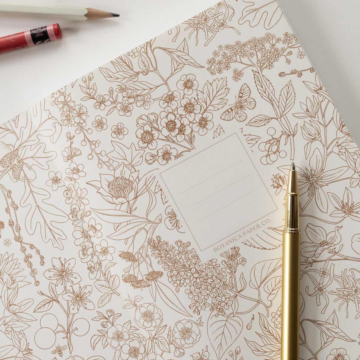 Floral patterned paper with a gold pen on a white surface