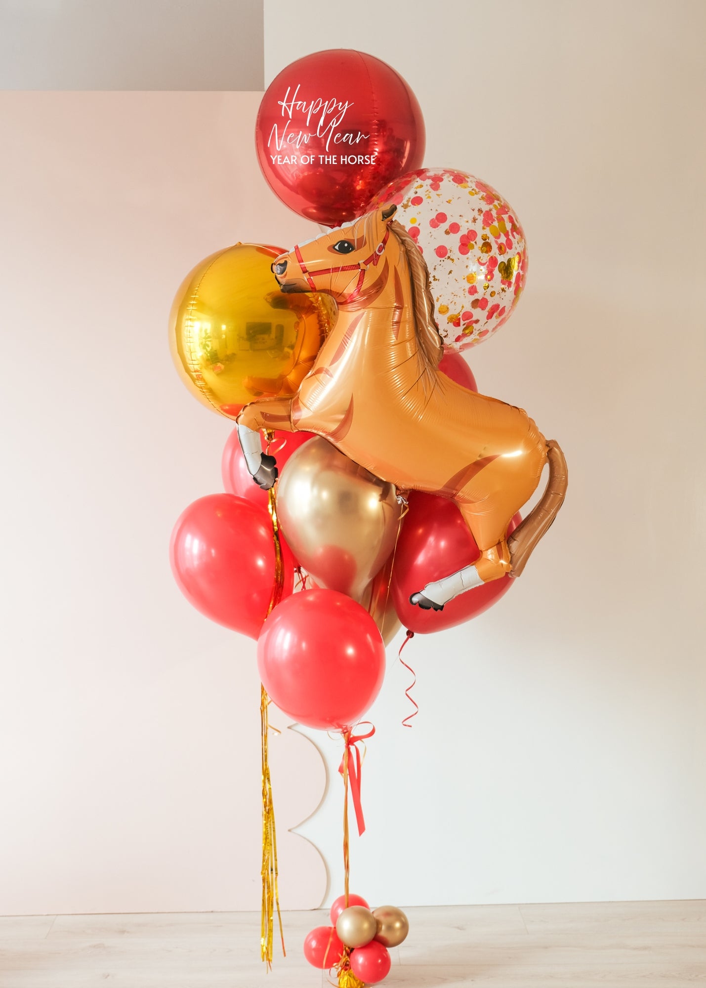A balloon bouquet celebrating lunar new year, with a horse, red, gold, and confetti balloons