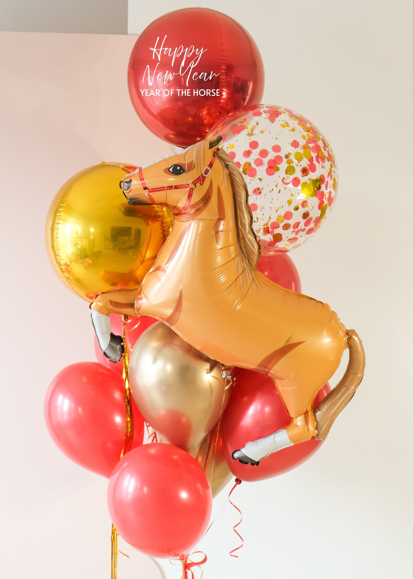 A balloon bouquet for year of the horse, with red, gold, and confetti balloons