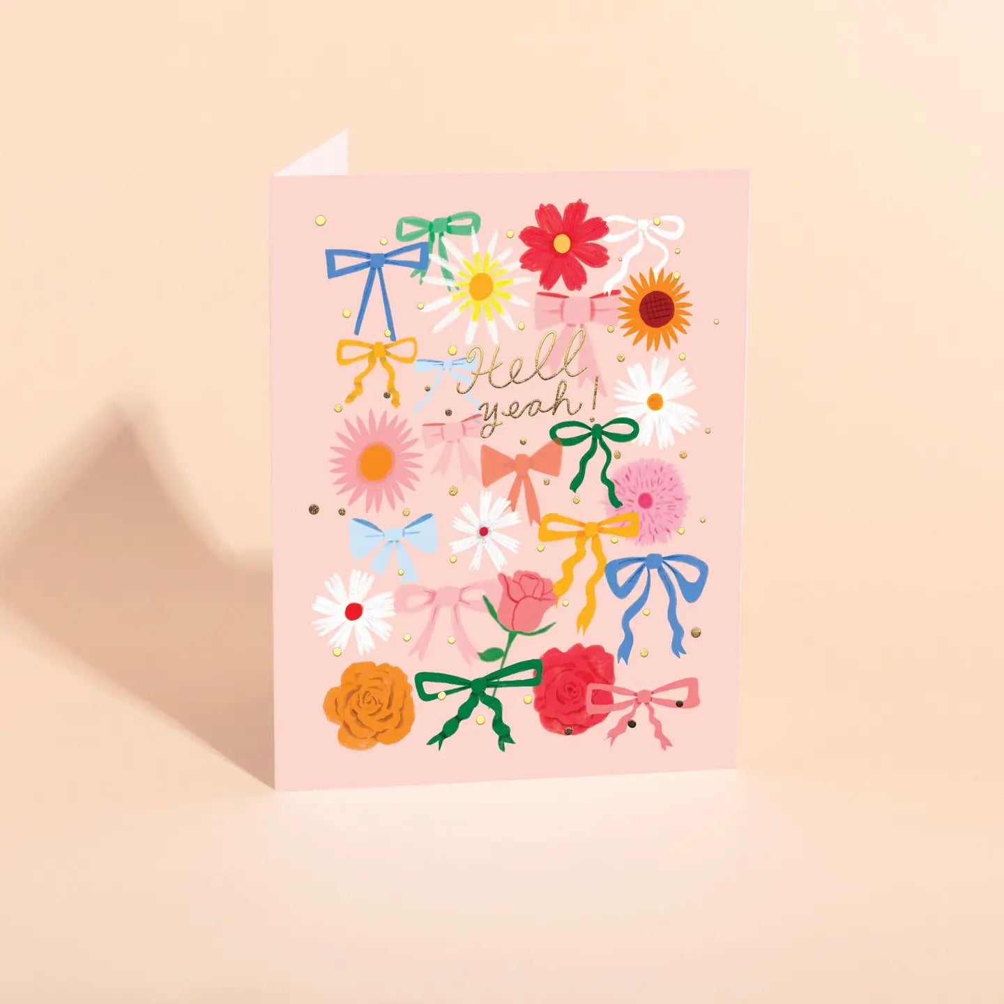 pink card with colorful bows and flower pattern, text "hell yeah!" in gold