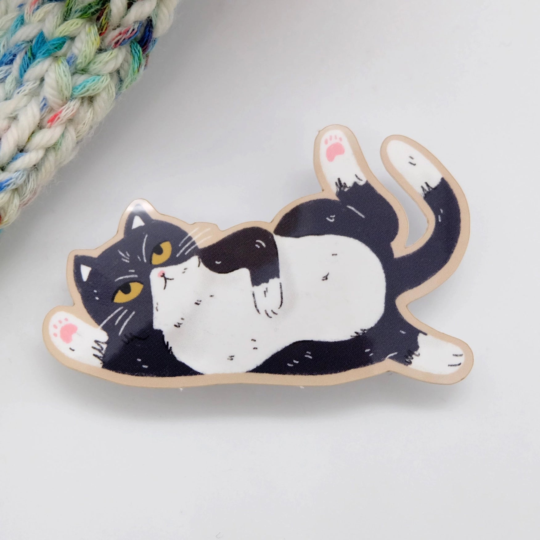 Cat-shaped sticker laing on its side on a white background