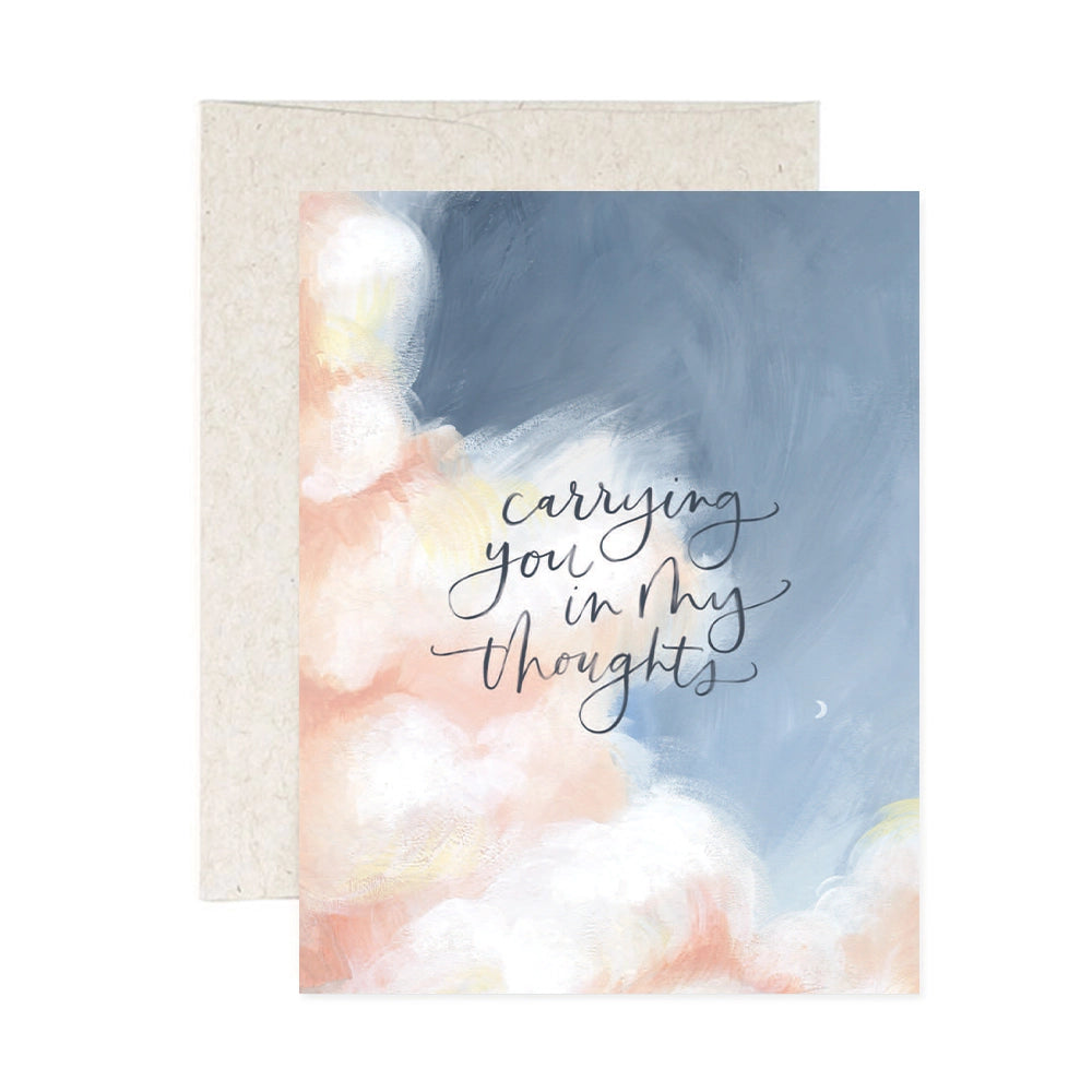 A sympathy greeting card with a watercolor illustration of clouds and the text 'carrying you in my thoughts' on the front.