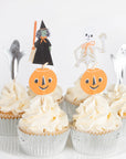 Halloween themed cupake toppers on white frosted cucpakes. Paper toppers include two ghost, pumpkins, witch, and skeleton 