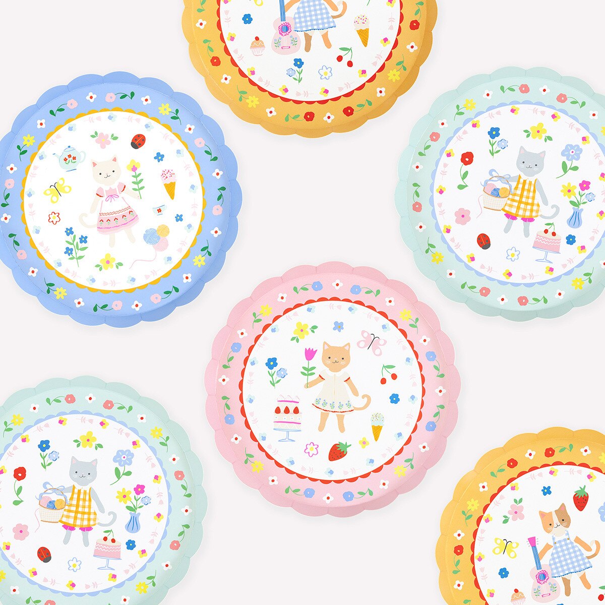 Set of colorful plates with cartoon cat characters and floral designs on a white background