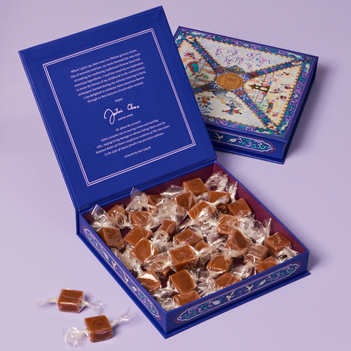 Open blue box filled with caramels and a smaller decorative box on a light purple background