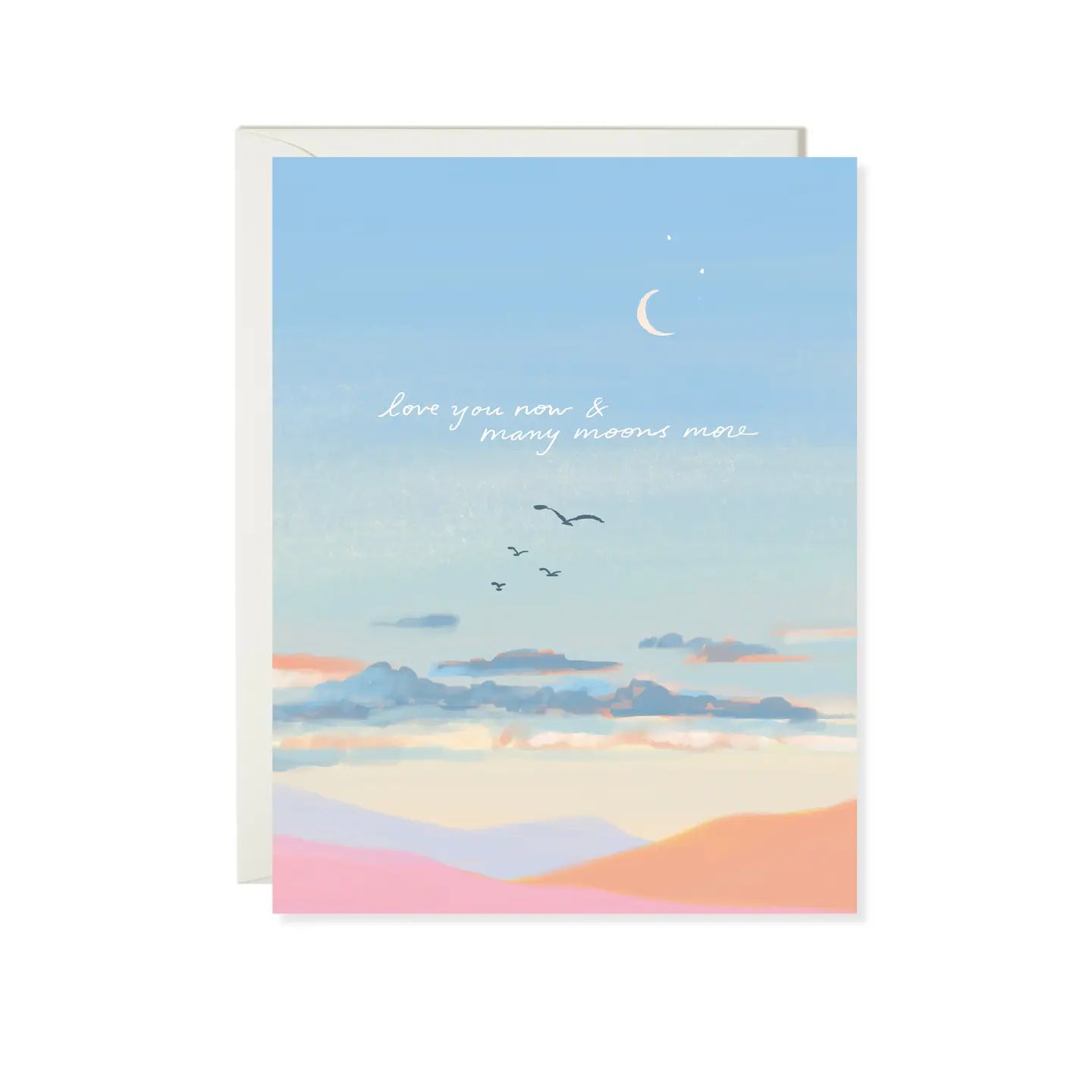 A folded greeting card with a blue sky and moonlit landscape, featuring text that says 'love you many moons' and includes a graphic of birds flying against a sunset background.