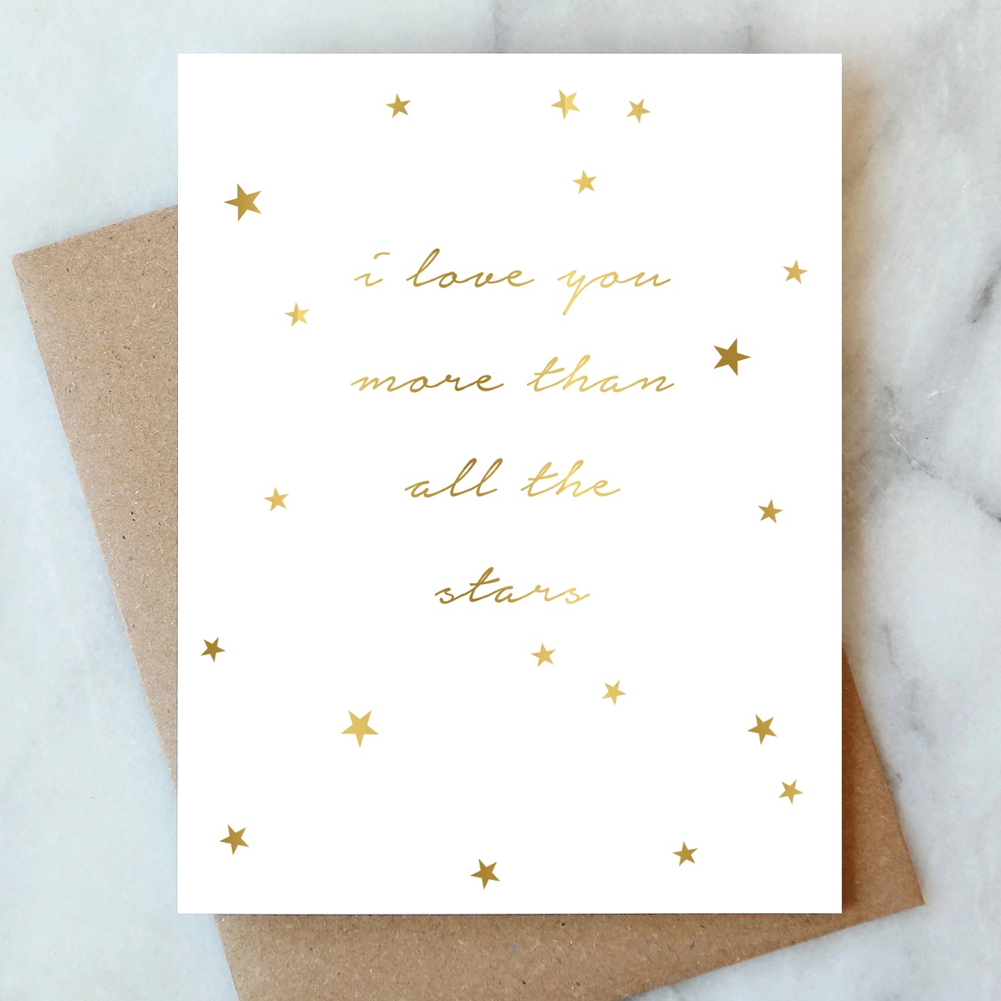 Greeting card with 'I love you more than all the stars' text and gold stars on a marble surface.