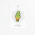 A small enamel pin shaped like a soft-ice cream cone with green swirls, a yellow cone, and a waffle-patterned base, attached to a white display card that reads 'a jar of pickles'.