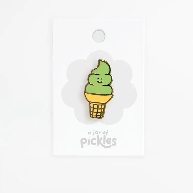 A small enamel pin shaped like a soft-ice cream cone with green swirls, a yellow cone, and a waffle-patterned base, attached to a white display card that reads 'a jar of pickles'.