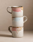 Stack of three ceramic mugs with marbled design on a beige background
