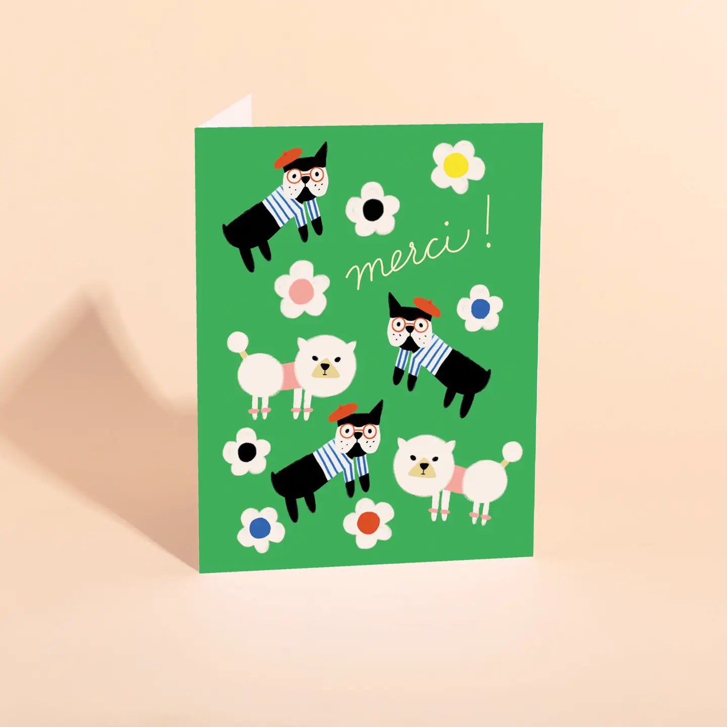 A colorful thank you card featuring cartoon dogs wearing striped hats, positioned against a green background with flowers. The word 'merci' is prominently displayed at the top.
