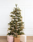 A green christmas tree draped with gold tinsel through and wrapped presents underneath the tree.