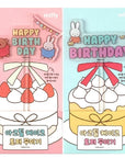A cake topped with a Miffy-themed topper, featuring cartoon-style rabbit characters and birthday greetings.