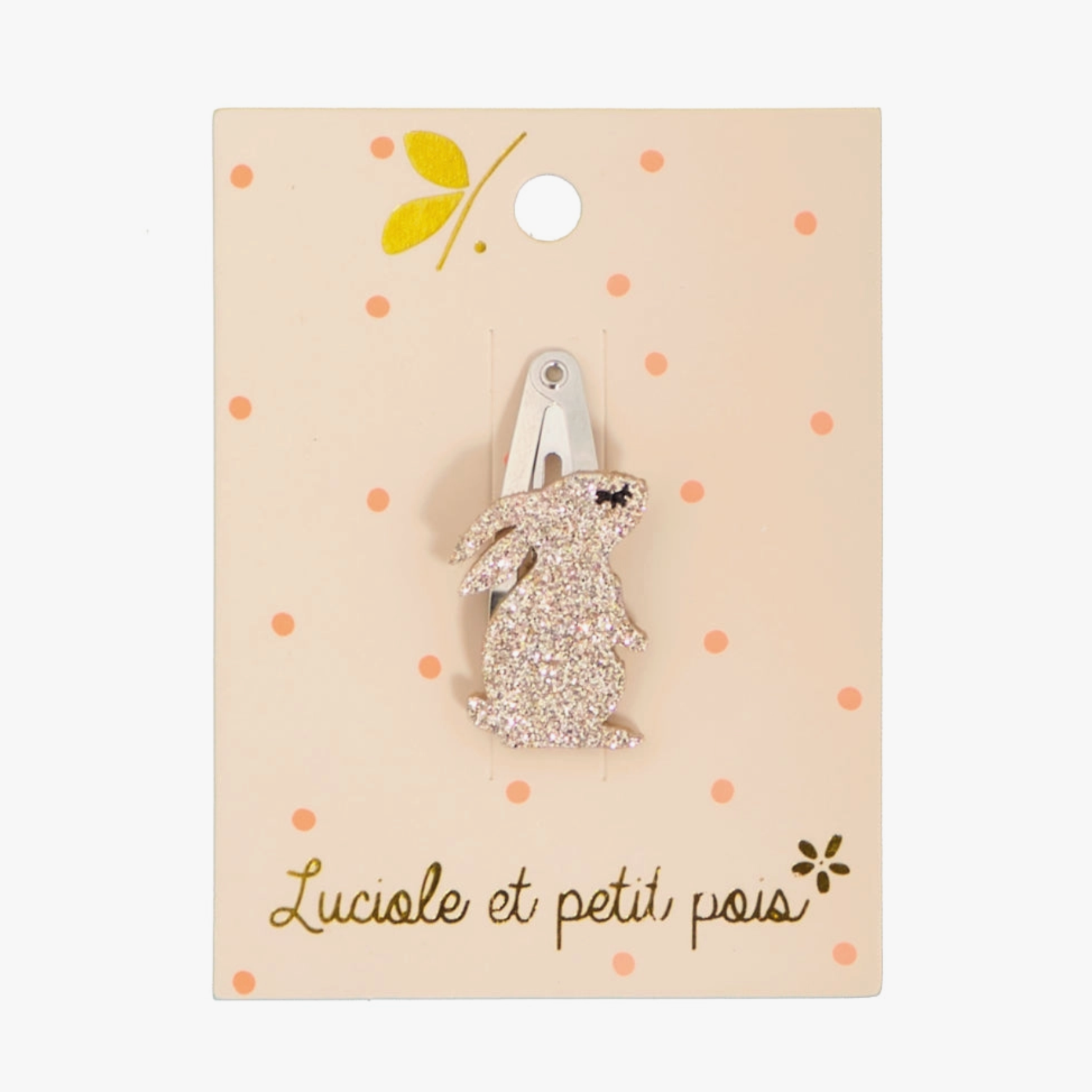 A mini sparkly rabbit hair clip on a beige background with polka dots, packaged on a card with a snap clip.