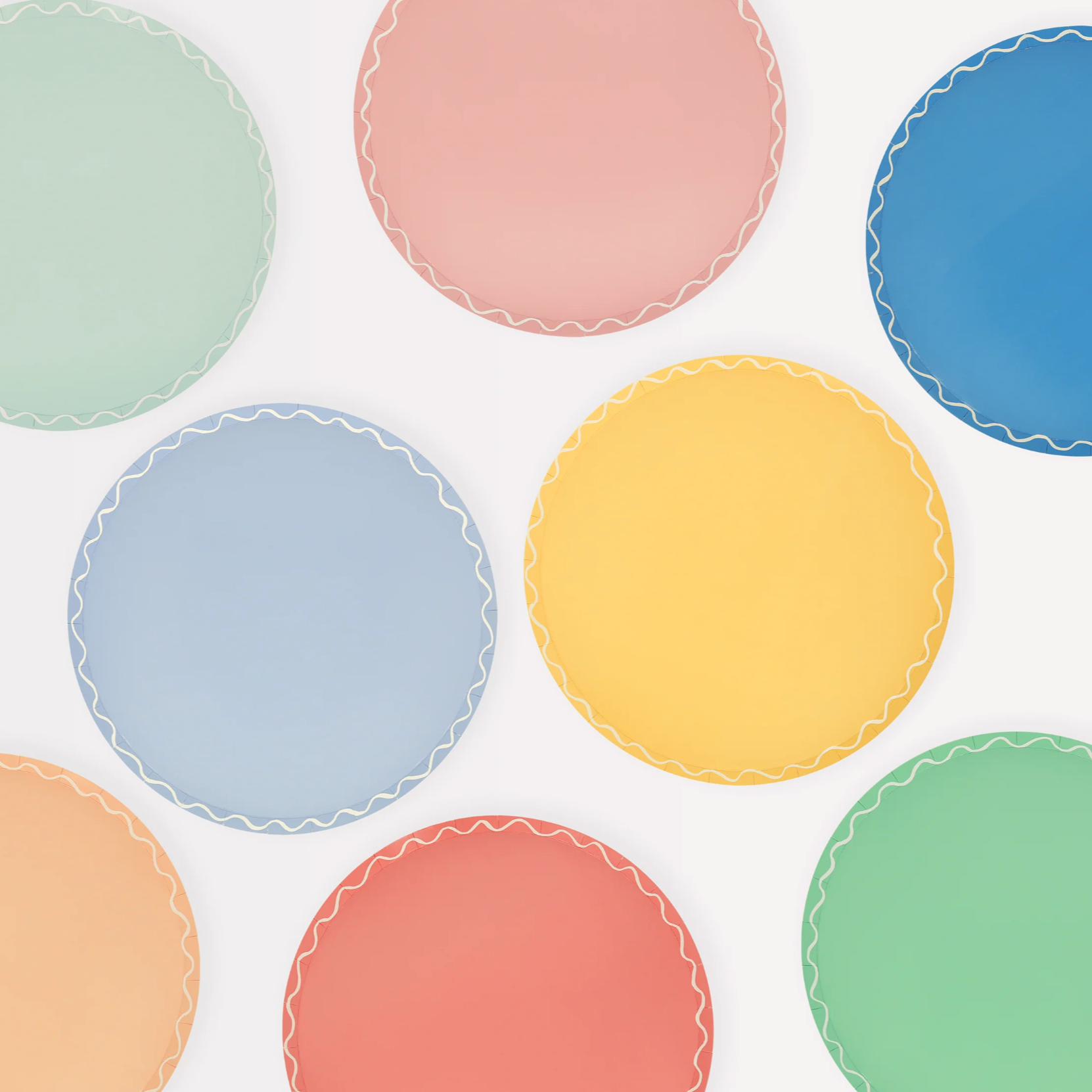A collection of round side plates in various pastel colors with a wavy line pattern along the border.