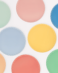 A collection of round side plates in various pastel colors with a wavy line pattern along the border.
