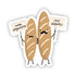 A sticker featuring two cartoon baguettes with faces and text signs that read 'more baguettes' and 'less regrets'. The baguettes are beige in color and have facial expressions.