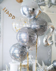 a set of round metallic balloons in silver, disco and confetti in front of a decorated backdrop