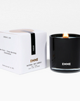 A black glass candle lit up next to a white box packaging