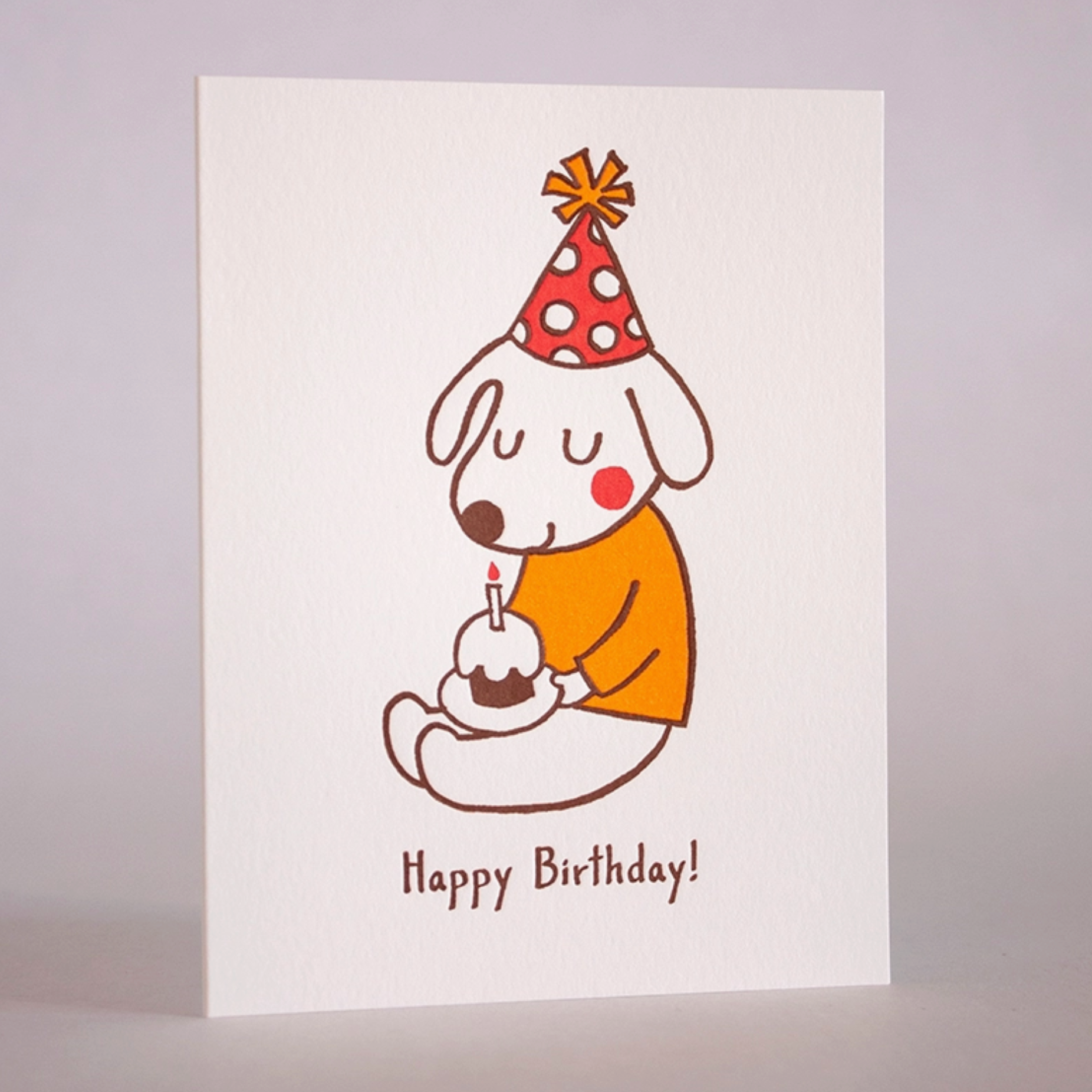 A greeting card with an illustration of a dog wearing a party hat and holding a birthday candle, with the text 'Happy Birthday!' and a space for a personal message.