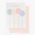 A greeting birthday card with pastel balloons in shades of pink, blue, and green, and gold foil text, enclosed in a pink envelope.