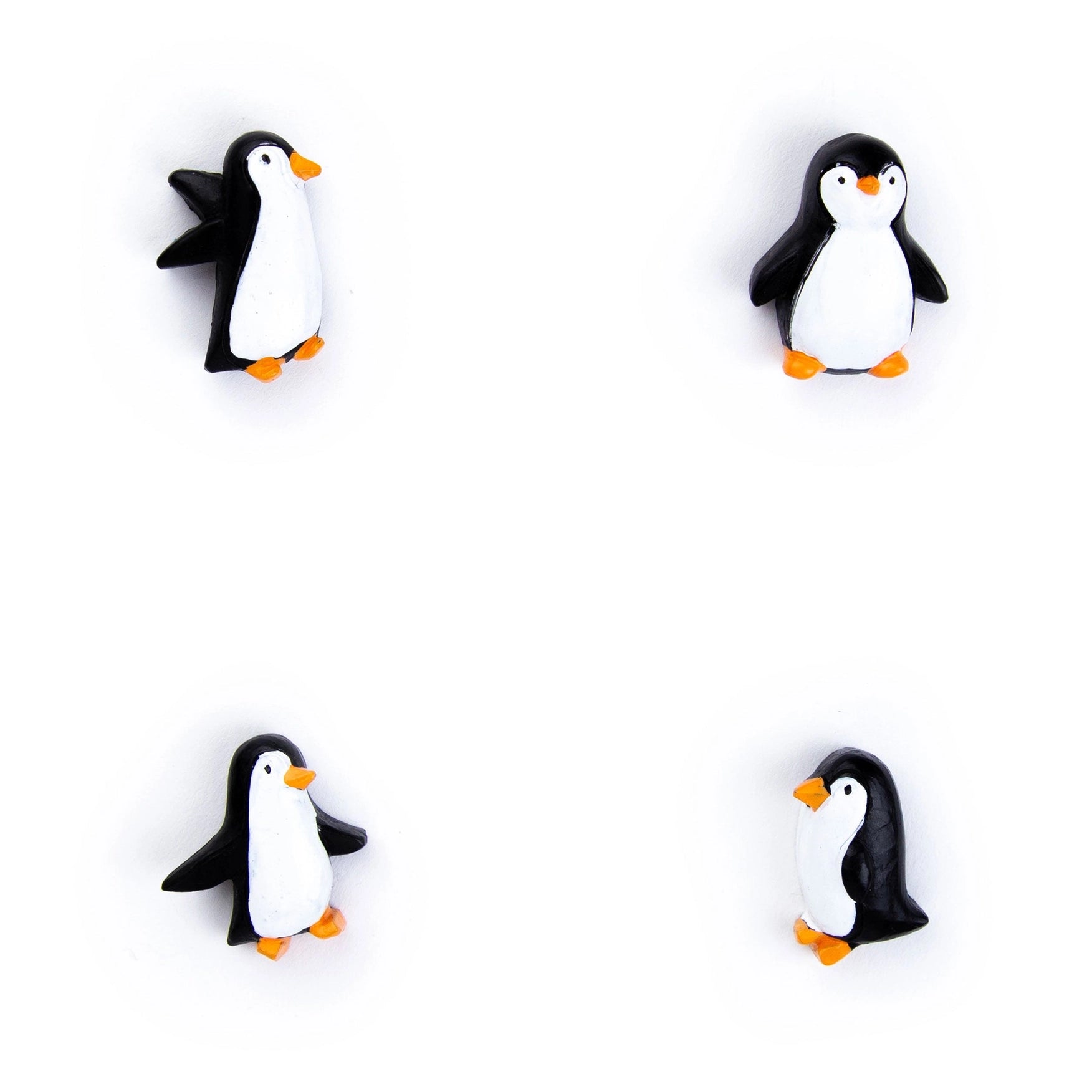 Four small penguin-shaped accessories arranged in a 2x2 grid on a plain white background. Each penguin is black and white with a small orange beak and orange feet.